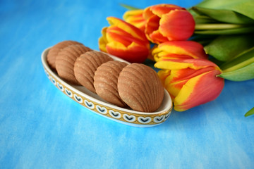 Fudge sweets and red tulips on blue background