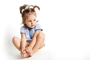 Pretty small kid with two pony tails, dressed in striped t shirt, looks thoughtfully away, dreams about something, isolated over white studio background for your advertisment or promotional text