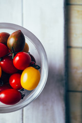 Freshly colored mixed  cherry tomatoes
inside a jar ,top view, over a blue background