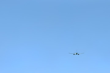 Fototapeta na wymiar The passenger plane flies away into the blue sky. Back view