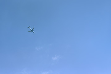 Passenger plane flies high against a blue sky background