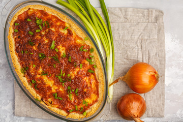 Traditional French onion pie. Quiche lorraine with onion, cheese and eggs in a glass oven dish, top view