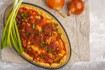 Traditional French onion pie. Quiche lorraine with onion, cheese and eggs in a glass oven dish, top view