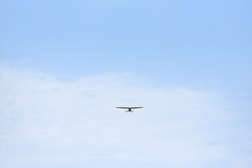 Fototapeta na wymiar Light propeller aircraft comes to land on a blue sky background