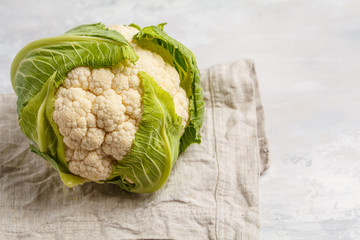 Ripe whole raw cauliflower on a light background on a napkin. Healthy vegan food concept.