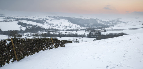 Beautiful snow covered Winter landscape at sunrise in Peak District in England
