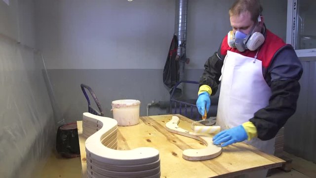 Industrial carpenter worker varnishing on wood dolly shot