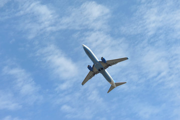 Fototapeta na wymiar The passenger plane flies low overhead on a blue sky background. Bottom view