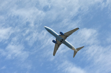 Fototapeta na wymiar The passenger plane flies low overhead on a blue sky background. Bottom view