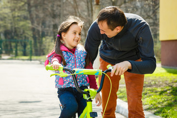 Father Teaching Daughter To Ride Bike In Garden
