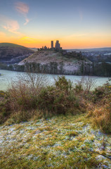 Beautiful Medieval castle ruin in countryside landscape during Winter sunrise