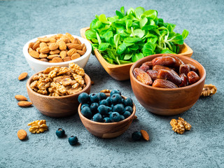 Healthy vegan food - dry fruits, greens, nuts, berry. Superfoods on gray stone background, side view.