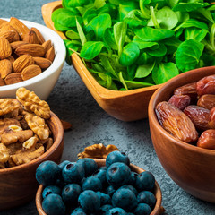 Healthy vegan food - dry fruits, greens, nuts, berry. Superfoods on gray stone background, side view, close up.