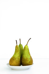 three ripe pears in white plate on a saucer on a white background