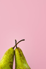 upper part of two wet ripe pears on a trendy pink background