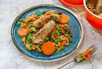 Sausage and bean casserole with carrots and green peas - top view