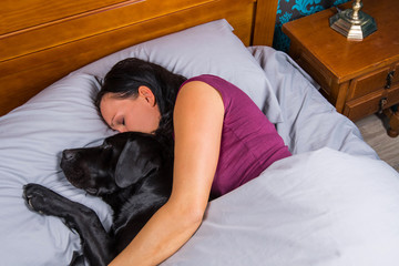 Woman sleeping in bed with dog.