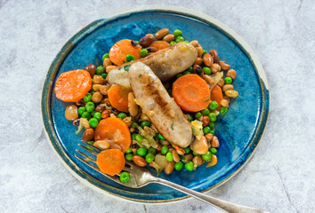 Sausage and bean casserole with carrots and green peas - top view