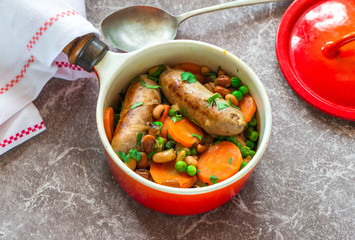 Sausage and bean casserole with carrots and green peas - top view