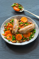 Sausage and bean casserole with carrots and green peas - top view