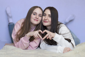 Portrait of two sisters lying on the floor smiling.