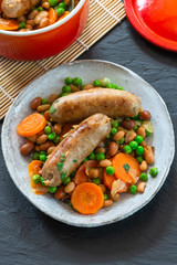 Sausage and bean casserole with carrots and green peas - top view