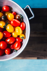 Freshly washed mixed cherry tomatoes
inside a colander over a rusty granite blue background
