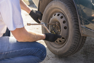 Mechanic changing wheel on car with a wrench.