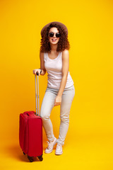 Woman traveler with suitcase on color background.