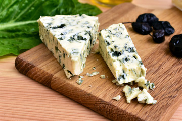 Blue cheese peaces on a wooden board on a kitchen table.