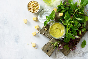 Homemade pesto sauce - traditional Italian green basil sauce with pine nuts, basil and parmesan on stone background. Copy space, top view flat lay background.