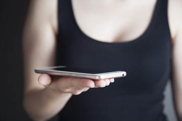 young woman holding smart phone on dark background