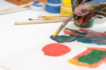 Obraz premium A child's hand in paint paints gouache on white paper.