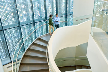 Interior of spacious office building with spiral concrete staircase and stylish design, two...