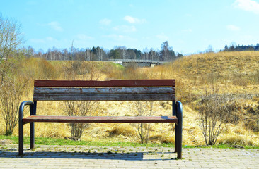 Old lonely empty brown wooden bench at pavement for rest.