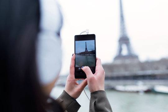 Back view of woman taking photograph of Eiffel tower from the river Seine in Paris.