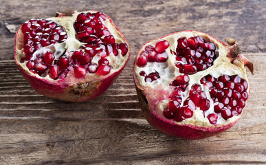 two halves of ripe pomegranate on wooden background