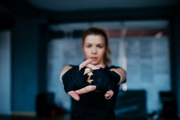 Woman stretching hands with boxing bandage toward camera.