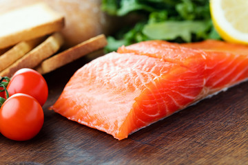 salmon fillet with vegetables and bread on wooden background