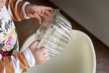 Learning to recycle concept: little baby-girl (toddler) throwing plastic container to recycling bin