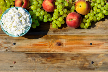 Plate of homemade cottage cheese, grapes and peach on wooden rustic table.Copy space for text.