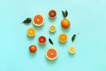 Fresh citrus fruits split on turquoise background.