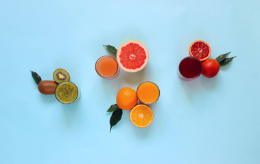 Fresh juices and fruit cut into slices on a turquoise background