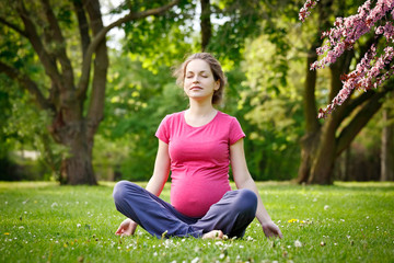Naklejka na ściany i meble Beautiful pregnant woman relaxing in the spring park