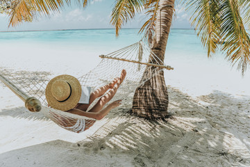 Maldive islands. girl is relaxing in hammock and reading book