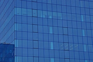 blue glass texture of windows on the wall of a tall building