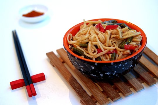 Cooked in wok noodles in Chinese style with chicken, green beans and sweet pepper