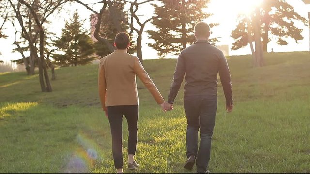 Gay couple walking together holding hands. The concept of same-sex relationships