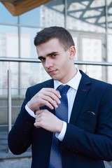 elegant young fashion man looking at his cufflinks while fixing them