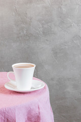 Obraz na płótnie Canvas Background with white cup of tea or milk on the table coated with pink tablecloth